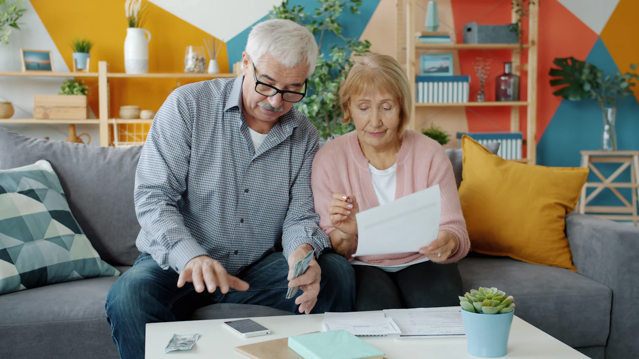 An older couple reviewing papers together on their sofa at home